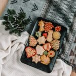 A collection of decorated Christmas cookies on a black tray with holiday patterns, perfect for festive celebrations.